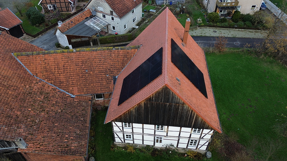 Drohnenaufnahme von Fachwerkhaus mit mit Photovoltaikanlage auf dem roten Ziegeldach