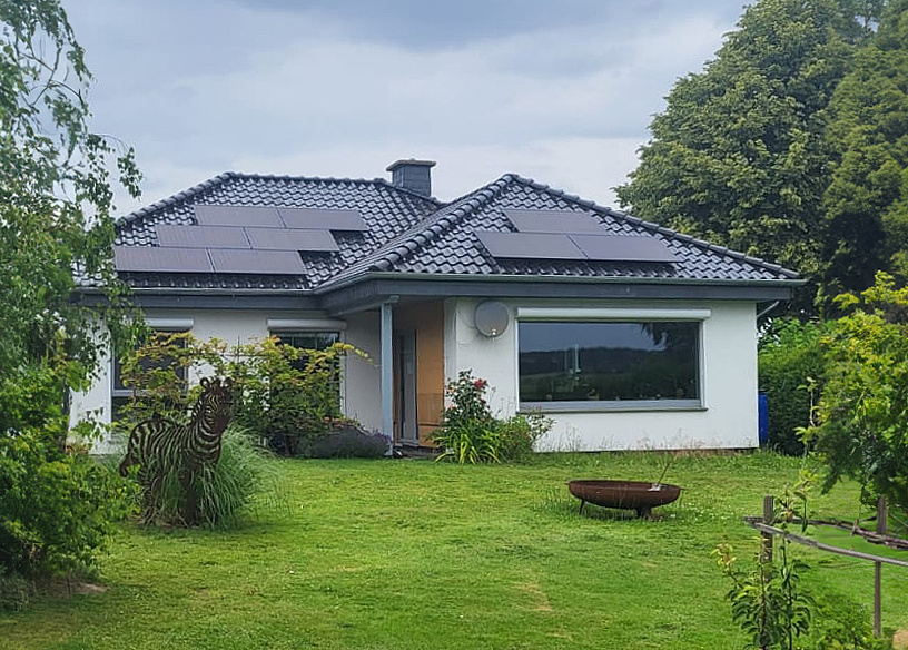 Gartenanicht eines Bungalows mit Photovoltaik auf dem Dach