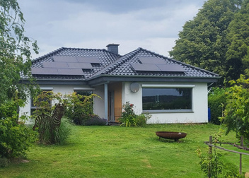 Gartenanicht eines Bungalows mit Photovoltaik auf dem Dach