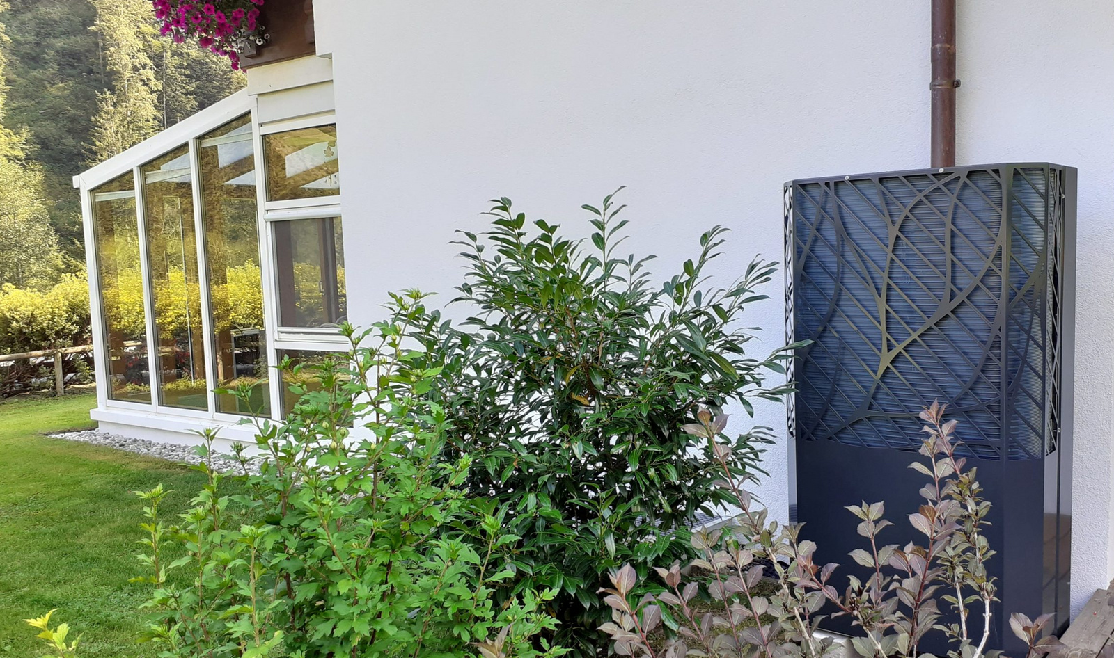 Eine Wärmepumpe von Lambda vor der Hausfassade im Garten