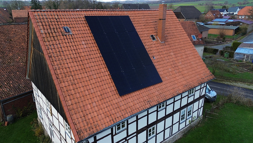 Drohnenaufnahme von Fachwerkhaus mit Photovoltaikanlage auf dem roten Ziegeldach