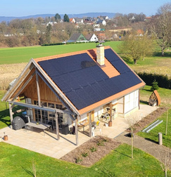 Drohnenaufnahme eines kleinen Einfamilienhauses mit Photovoltaikanlage auf dem Dach