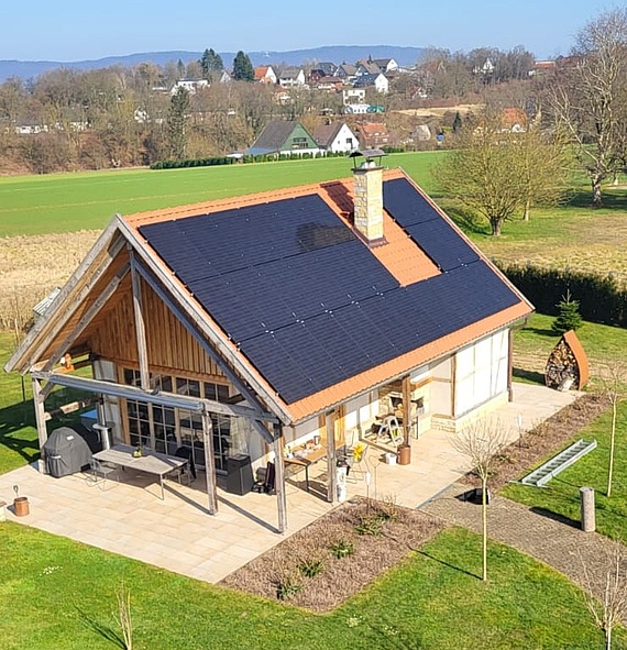 Drohnenaufnahme eines kleinen Einfamilienhauses mit Photovoltaikanlage auf dem Dach